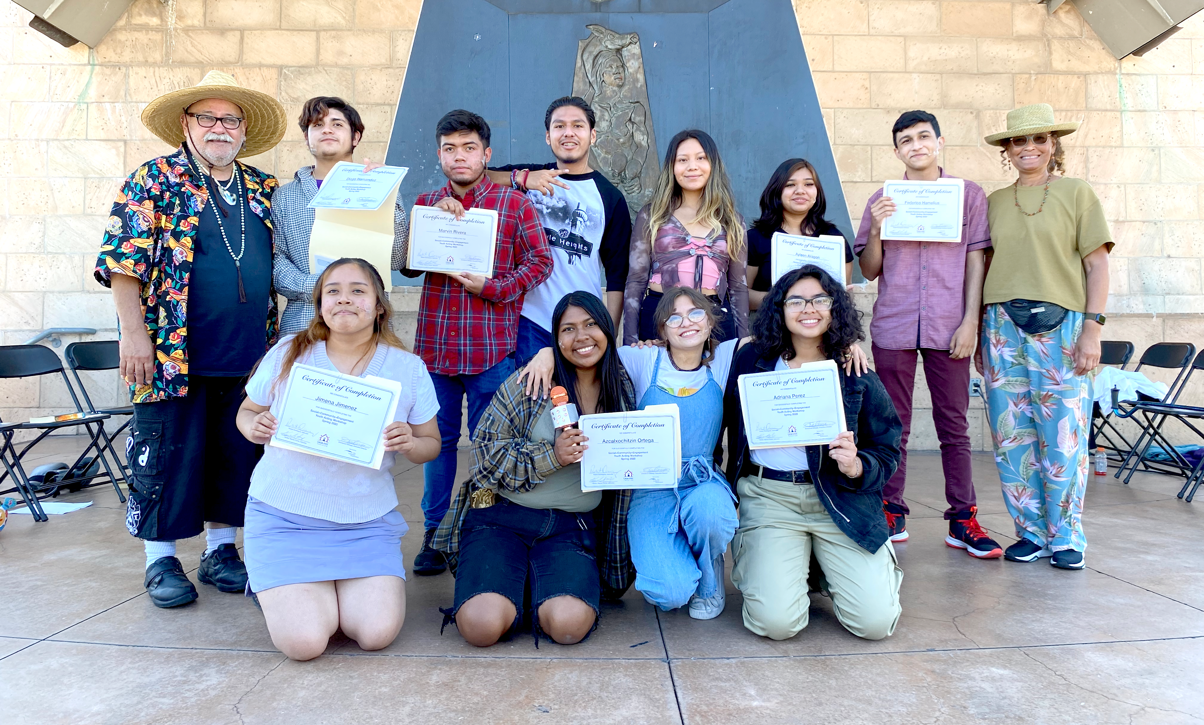 A group of high school students gather for a group photo while showing off their certificates.